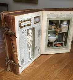 an open book with a skeleton in it on top of a wooden table next to a mirror