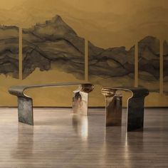 three metal benches sitting in front of a painting