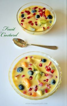 two bowls filled with fruit on top of a white table next to a silver spoon