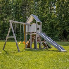 a wooden play set in the middle of a park with a slide and swing set