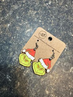 the grin face earrings have been painted with green and red colors on them, as well as santa claus's hat