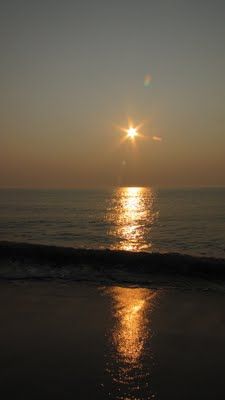 the sun is setting over the ocean with its reflection on the water's surface