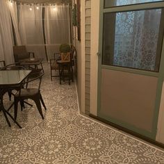 a room with a table and chairs next to a door that has curtains on it