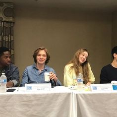 four people sitting at a table with water bottles