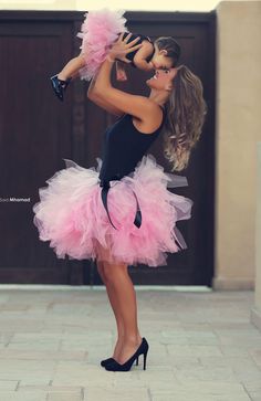 a woman in a pink and black dress is holding a small child up to her face