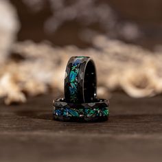 two rings with blue and green designs on them sitting on top of a wooden table