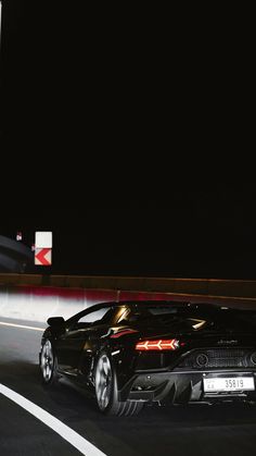 a black sports car driving down the road at night