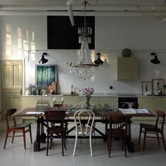 a dining room table with chairs and a chandelier hanging from the ceiling