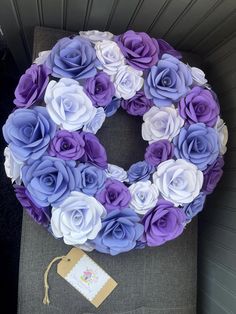 a purple and white wreath sitting on top of a gray chair next to a tag