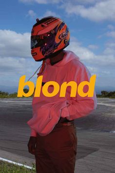 a man wearing a helmet and standing next to a road with the word blond on it