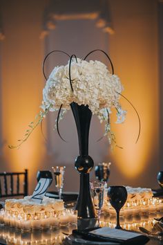 the centerpieces are arranged in black vases with white flowers and lit candles