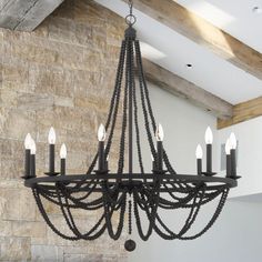 a chandelier hanging from the ceiling in a room with stone wall and exposed beams