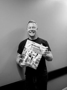 a man standing in front of a mirror holding up a magazine