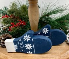 two wooden shoes sitting on top of a table next to pine cones and christmas decorations