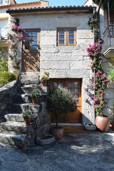 an old stone house with potted plants on the steps