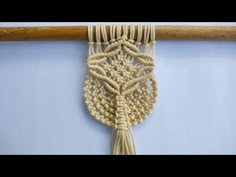 a close up of a piece of string art hanging on a wall next to a wooden stick