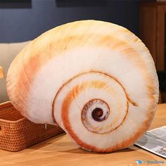 a close up of a stuffed animal snail on a wooden table next to a basket