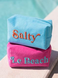 two personalized beach towels sitting on the edge of a swimming pool next to each other