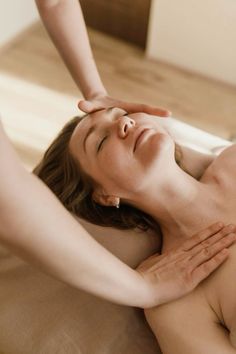 a woman getting a back massage with her hands on her head and the other hand over her face