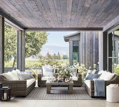 an outdoor living area with wicker furniture and wood plank ceilinging, overlooking the water