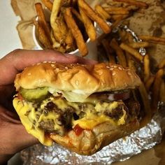 a hand holding up a cheeseburger and french fries