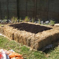 a hay bale filled with dirt next to a fence