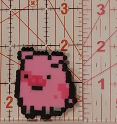 a pink and black cat pin sitting on top of a ruler