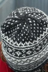 a close up of a person wearing a knitted hat with black and white designs