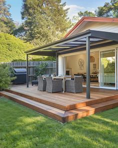 an outdoor deck with chairs and table in the grass next to a patio area that has sliding glass doors on both sides