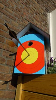 a birdhouse shaped like a target with an arrow sticking out of it's center