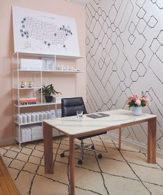 an office with a desk, chair and shelving unit on the wall behind it