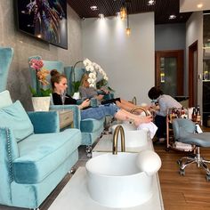 two women are getting their hair done in a beauty salon while another woman sits on the chair