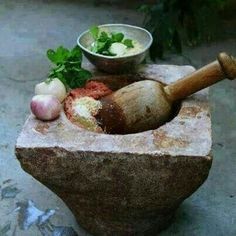 a mortar bowl with spices and herbs in it sitting on top of a cement block