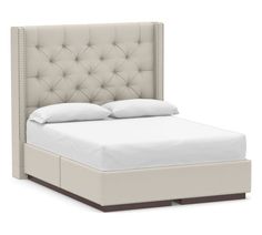 an upholstered bed with white linens and buttons on the headboard is shown