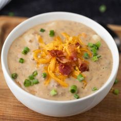 a white bowl filled with soup topped with cheese and bacon