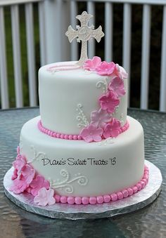 a white cake with pink flowers and a cross on top