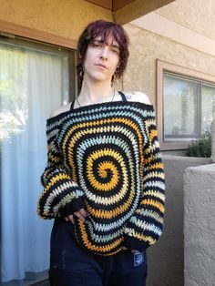 a woman standing in front of a building wearing a crocheted sweater