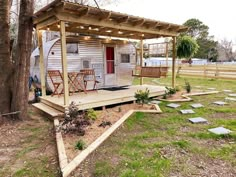 a mobile home with deck and lights on the porch next to a tree in front of it