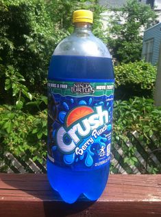 a bottle of crush gummy punch sitting on top of a wooden table next to trees