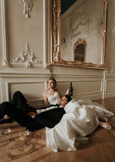 a bride and groom laying on the floor with champagne