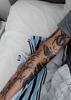 a person laying in bed with a tattoo on their arm