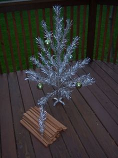 a silver christmas tree sitting on top of a wooden deck