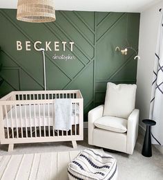 a baby's room with a white crib, chair and green accent wall