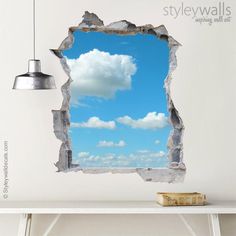 an open hole in the wall with a blue sky and white clouds as seen through it