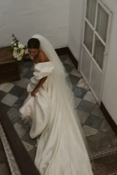 a woman in a wedding dress is walking down the stairs