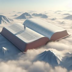 an open book with a man standing on top of it in the middle of clouds