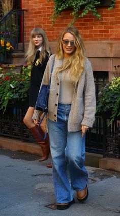 two women walking down the street with one carrying a handbag in her right hand