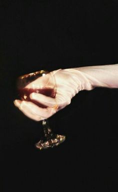 a woman's hand holding a wine glass in the middle of her left hand