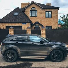 a black range rover parked in front of a brown brick house on a cloudy day