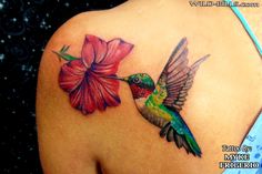 a hummingbird with a flower tattoo on its back shoulder and wings flying towards the viewer